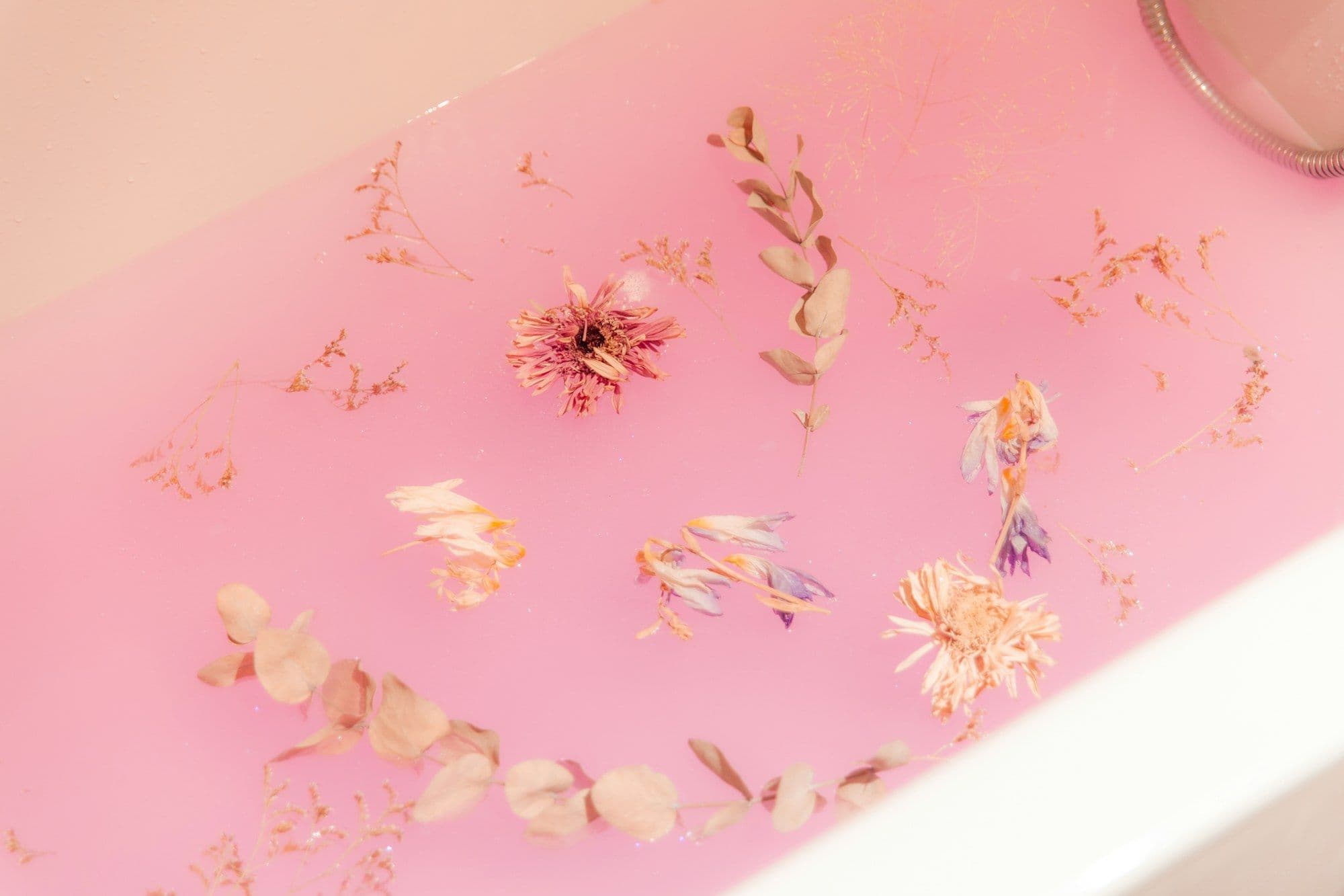 Dried flowers floating in a pink bath